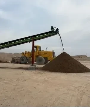 Loader beside a conveyor and aggregate stockpile